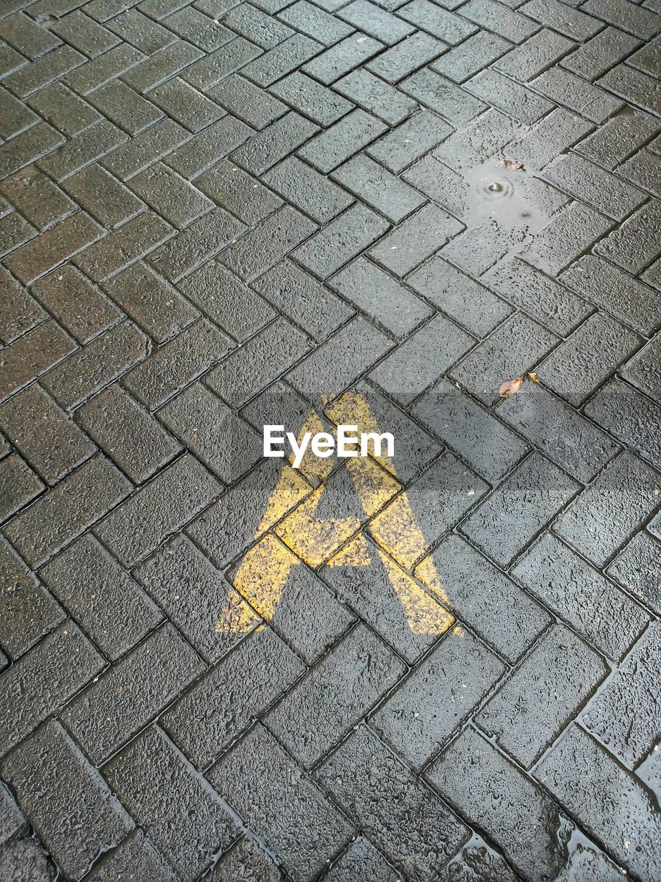 HIGH ANGLE VIEW OF YELLOW ARROW SYMBOL ON STREET