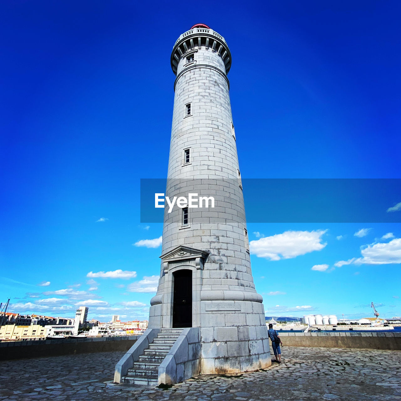 LIGHTHOUSE AMIDST BUILDINGS AGAINST SKY