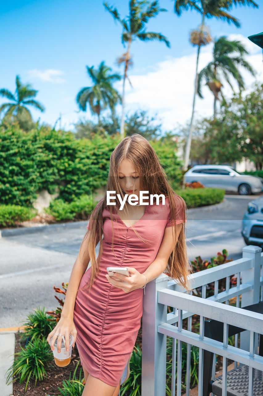 side view of young woman standing against trees