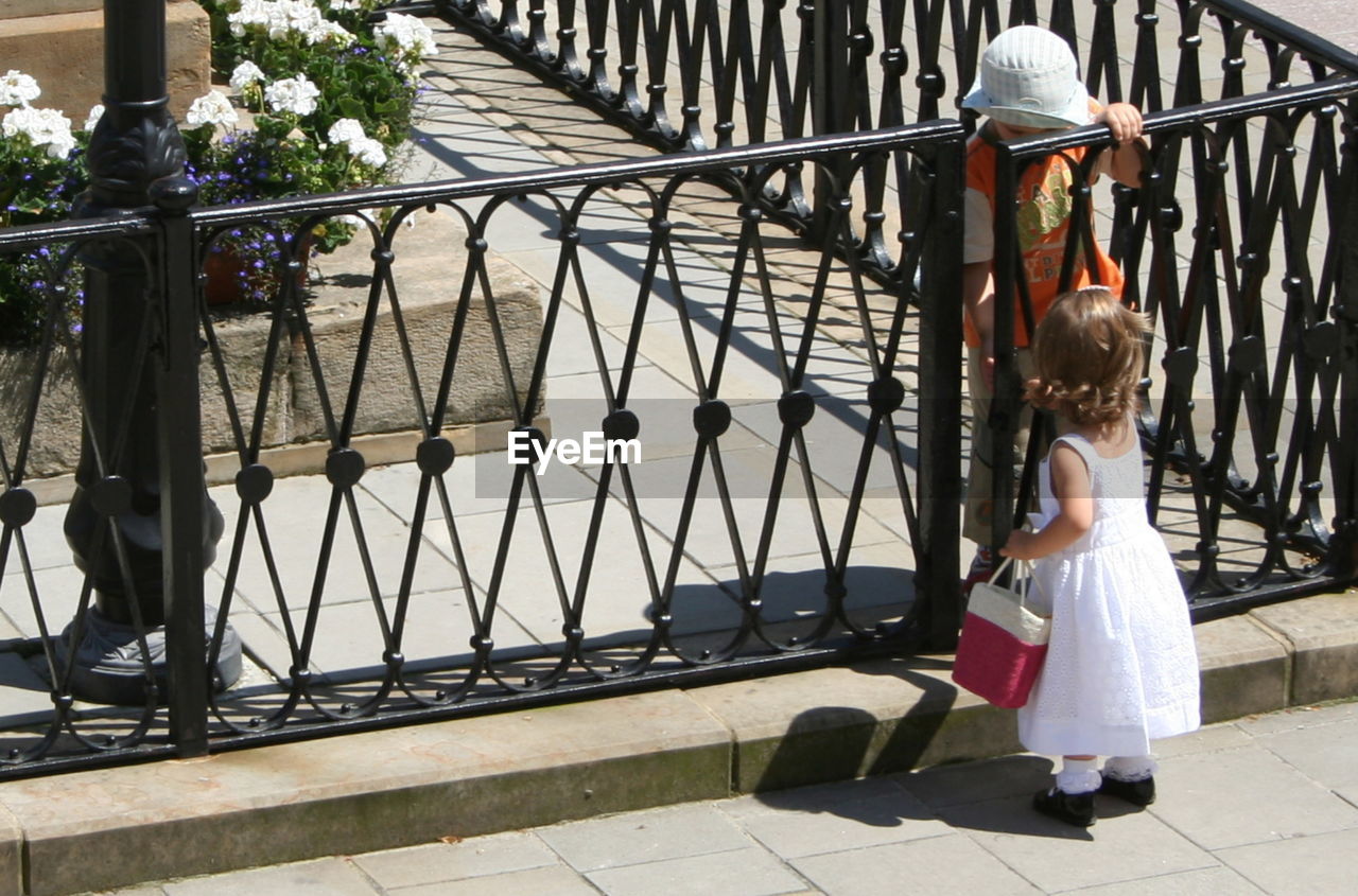 REAR VIEW OF GIRL WALKING BY RAILING