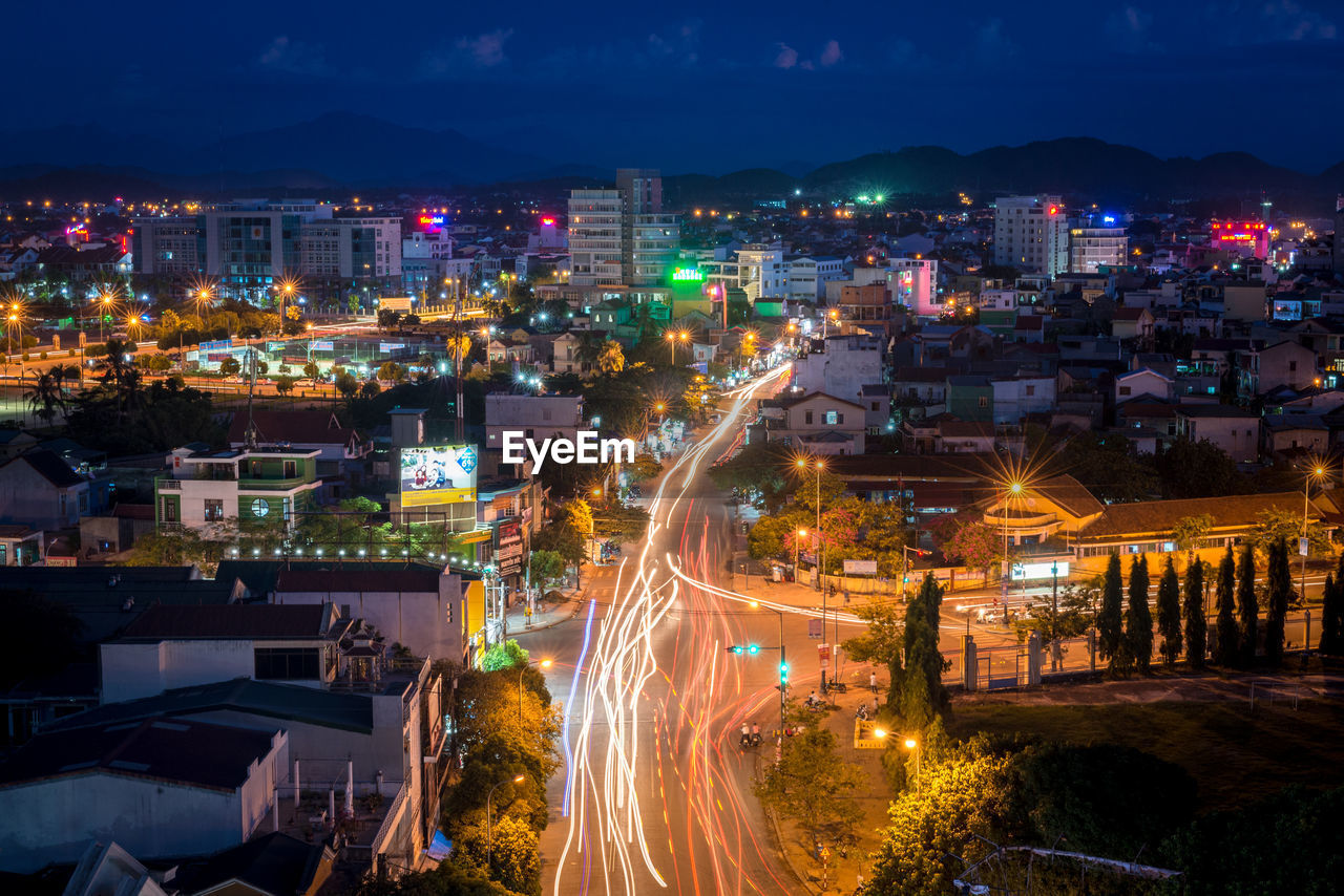 HIGH ANGLE VIEW OF ILLUMINATED CITY BUILDINGS AT NIGHT