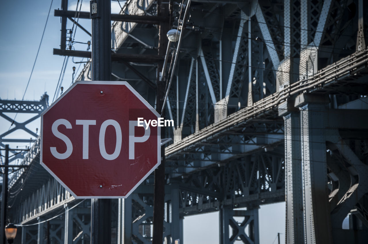 Close-up of stop sign against bridge