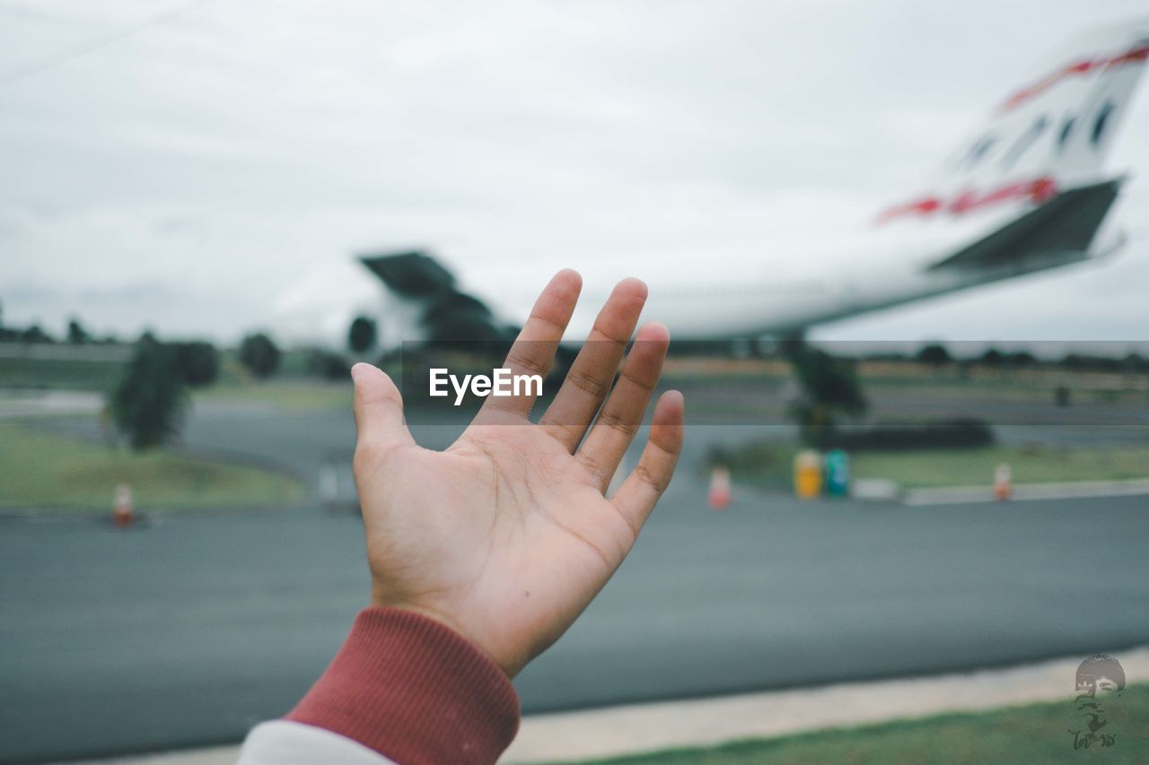 Close-up of person hand against sky