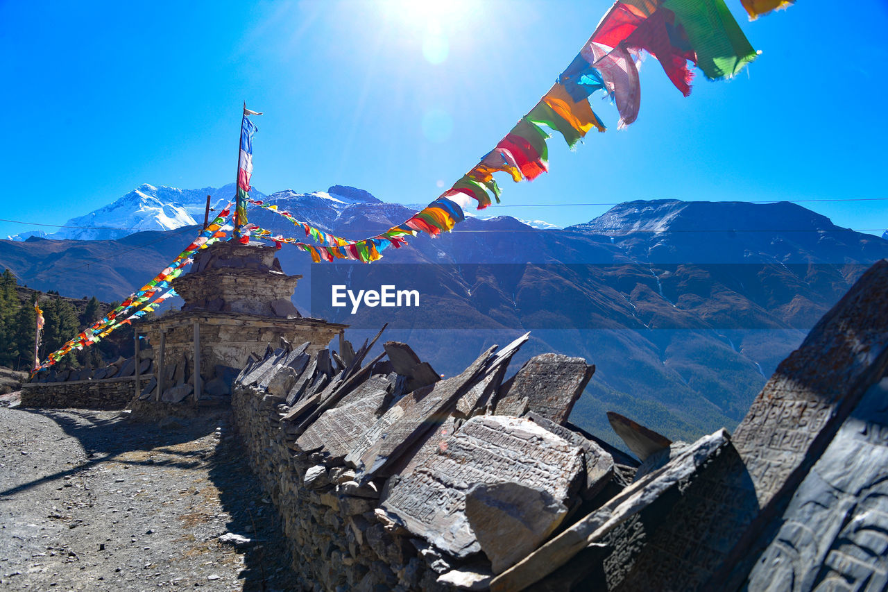 Colorful prayer flags hanging against mountains during sunny day