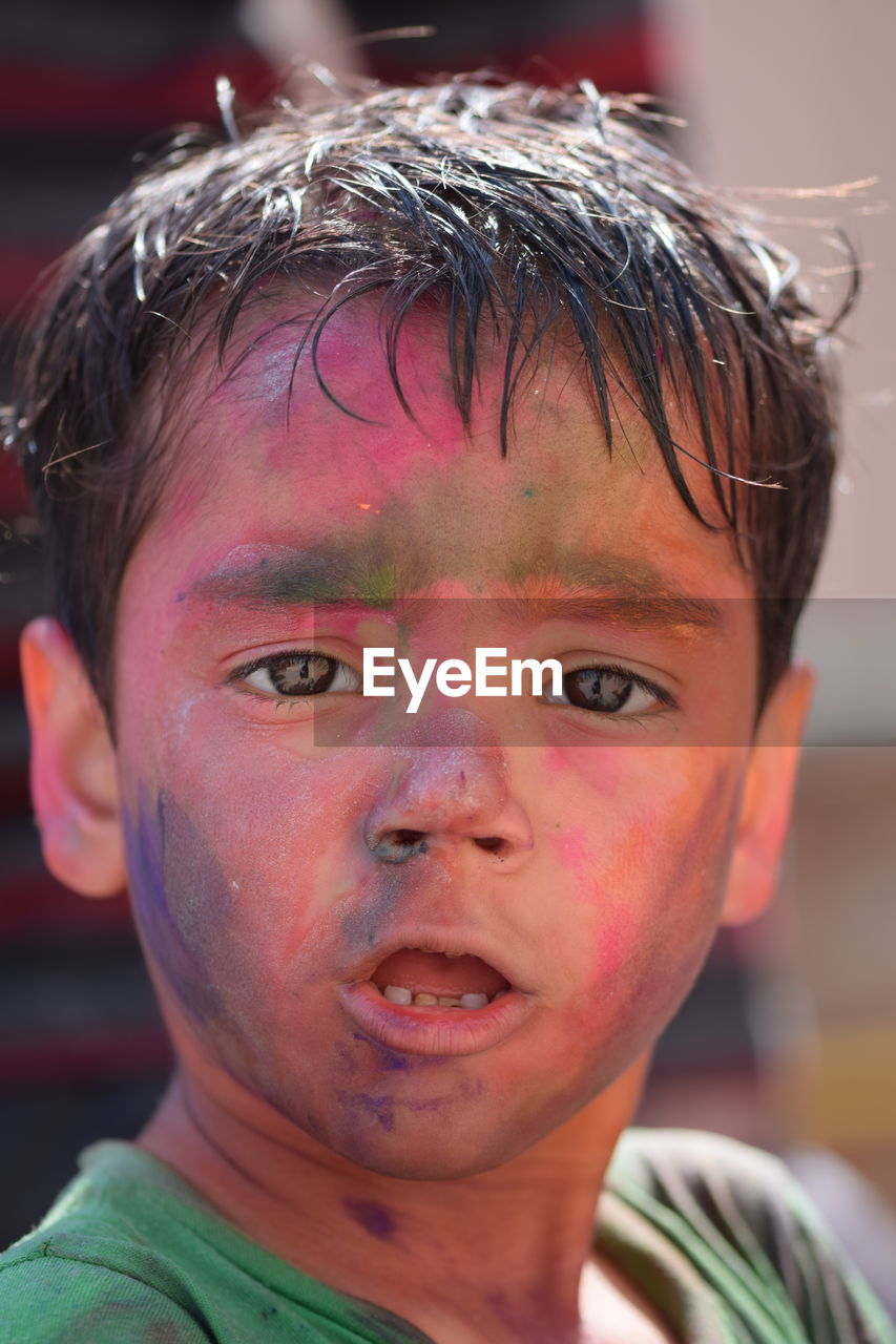 Close-up portrait of boy with powder paint on face during holi