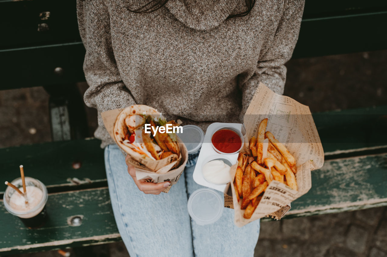 Midsection of women holding food while standing on a public area