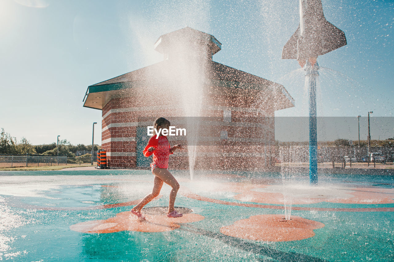 Cute adorable caucasian funny girl playing on splash pad playground on summer day. happy child 