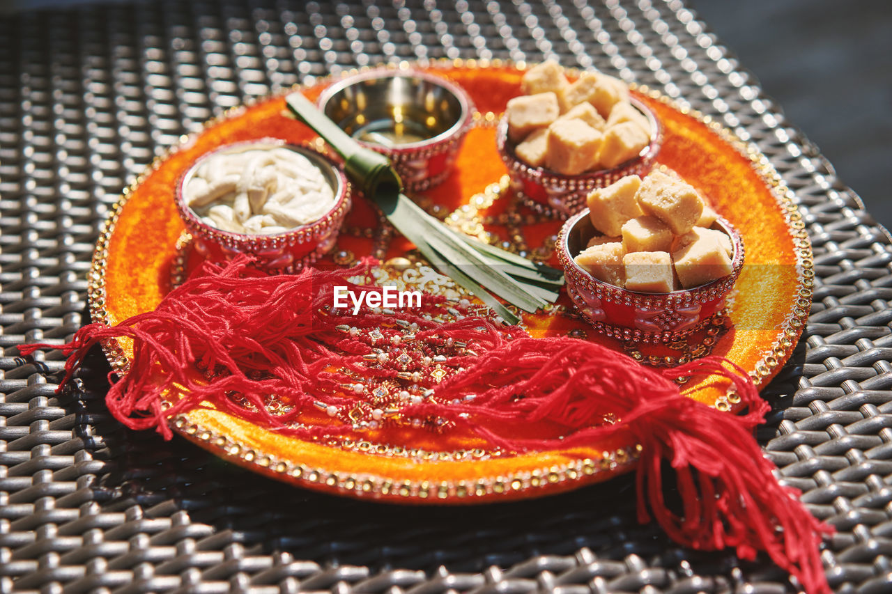 High angle view of rakhis with sweet food in plate during raksha bandhan on table