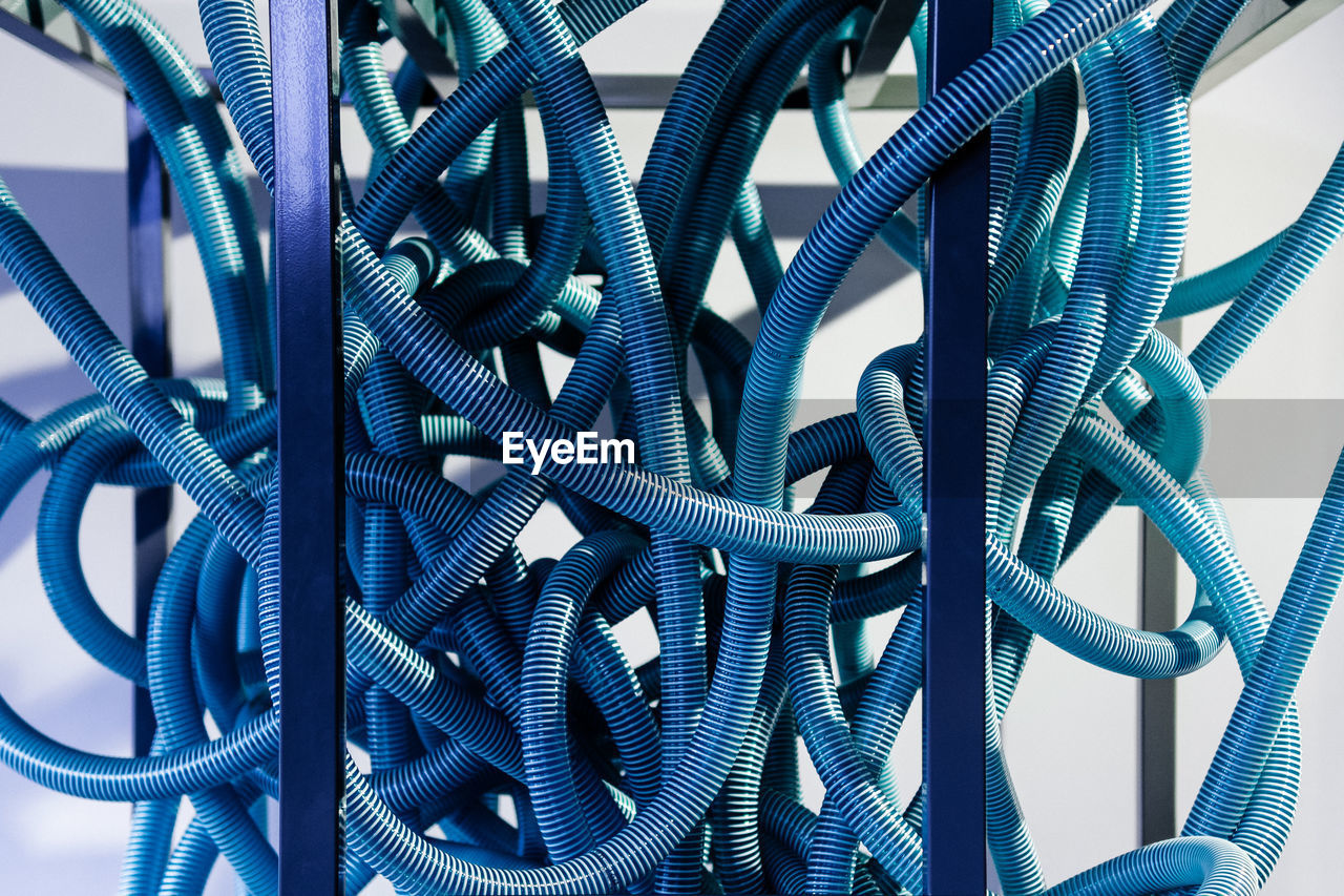 Close-up of blue tangled cables against wall