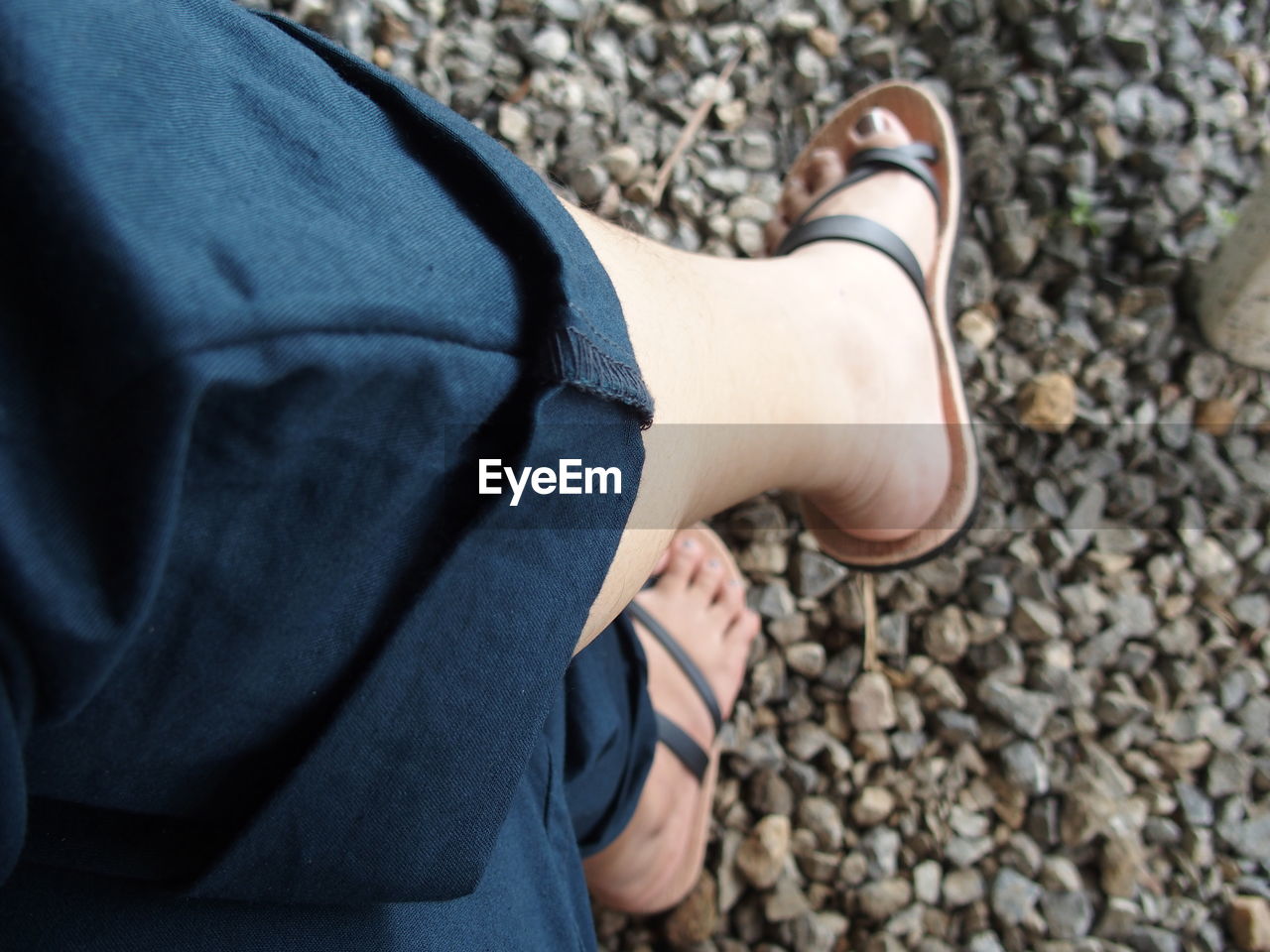 Low section of woman sitting on gravel