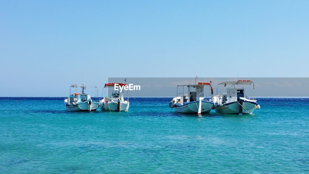 Boats in sea against clear sky
