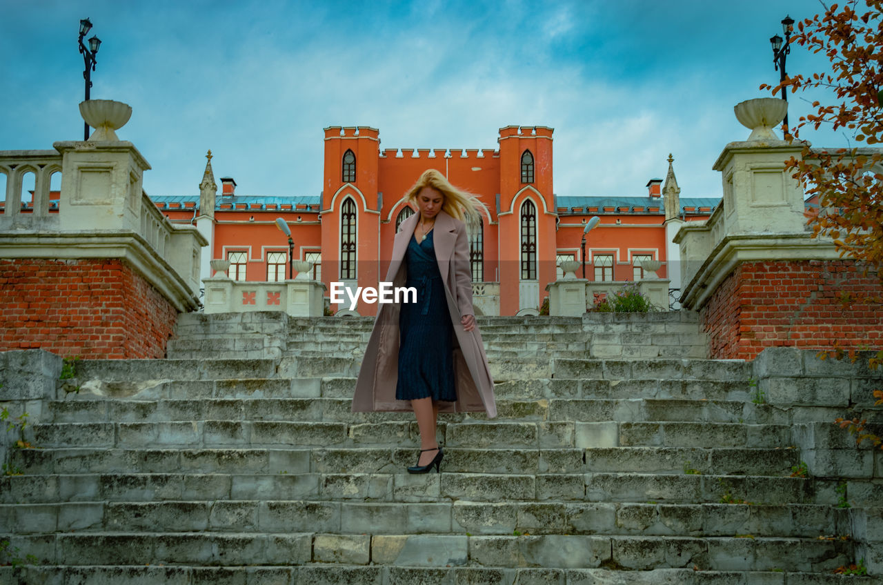 WOMAN STANDING BY BUILDING