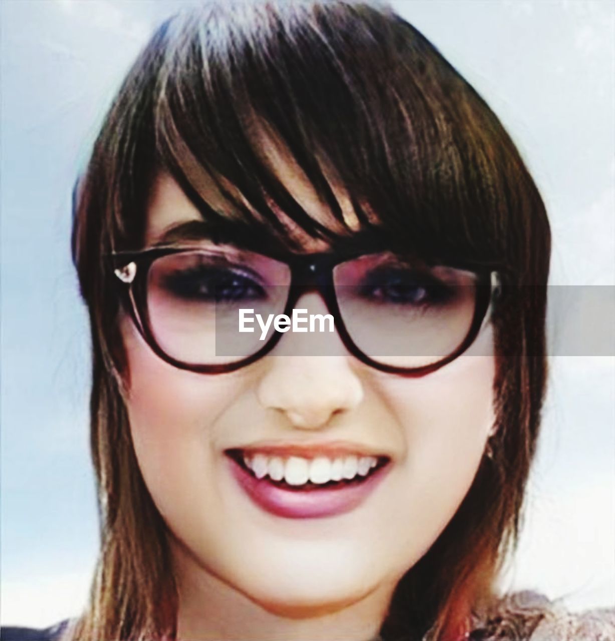 CLOSE-UP PORTRAIT OF SMILING YOUNG WOMAN WITH EYEGLASSES