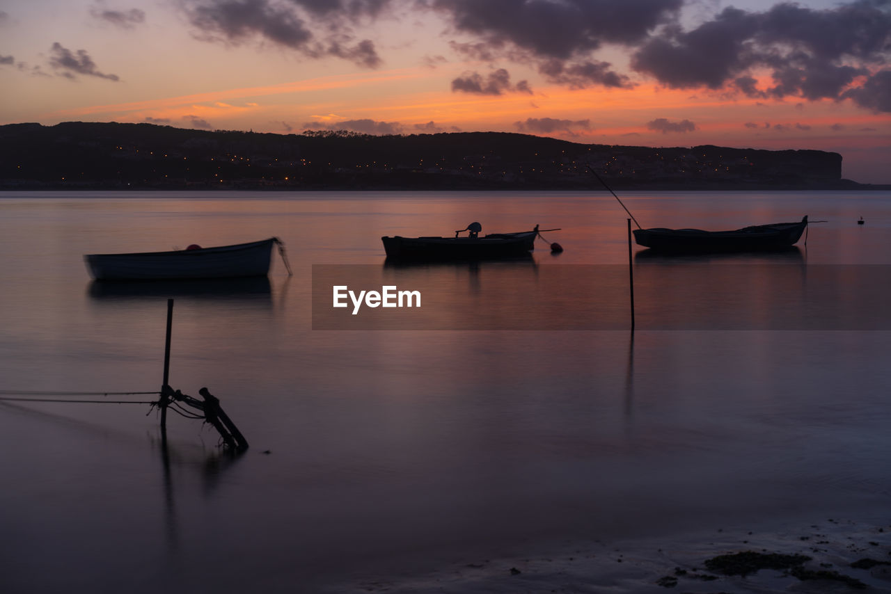 Fishing boats on a river sea at sunset in foz do arelho, portugal