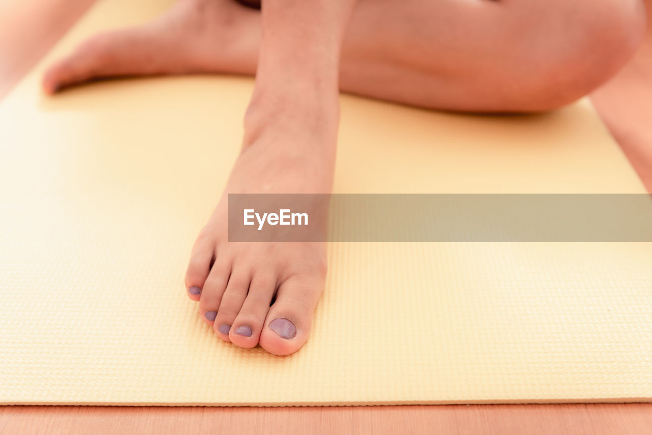 Low section of woman sitting on exercise mat