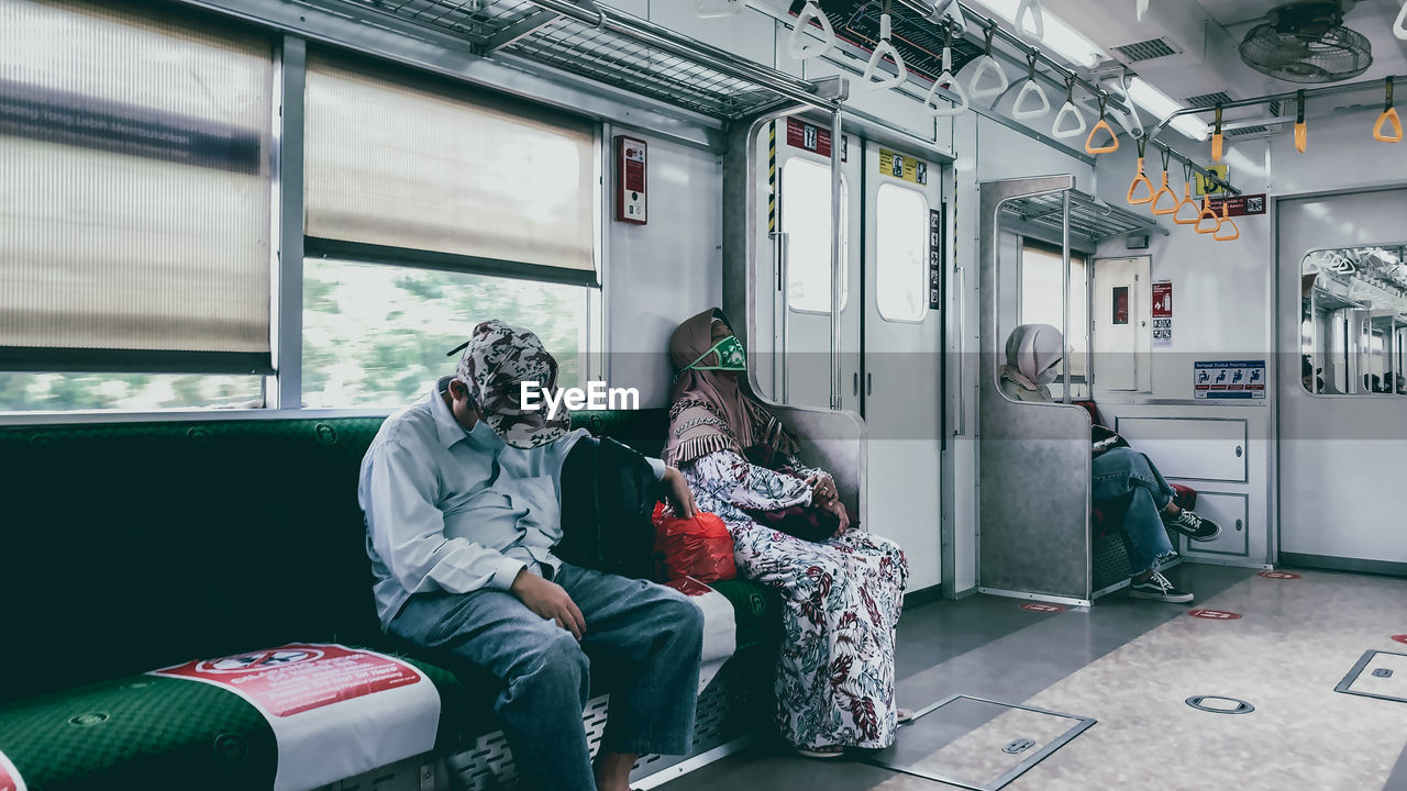 REAR VIEW OF MAN SITTING AT TRAIN