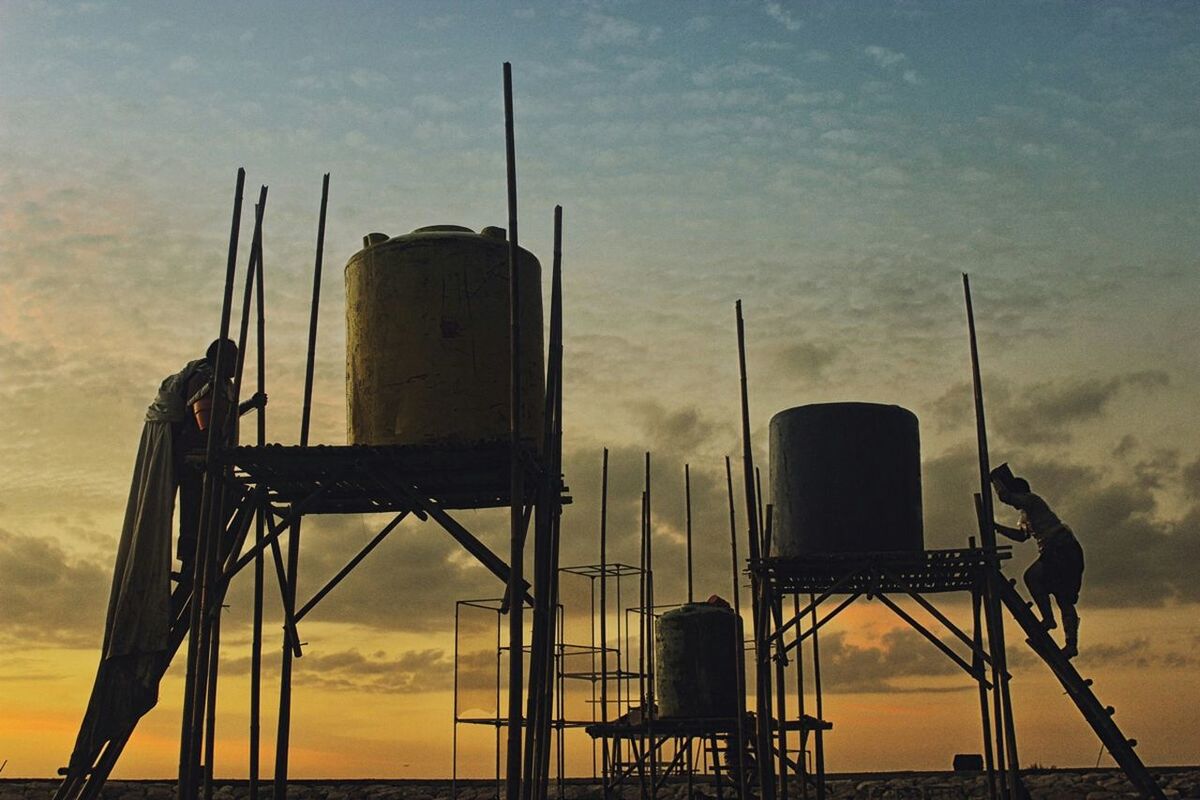 Low angle view of water tank by lake at dusk