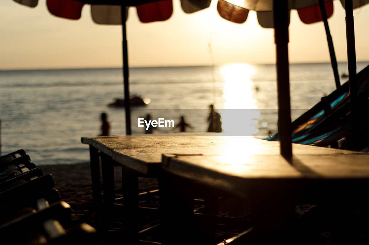 Chairs and table at beach against sky