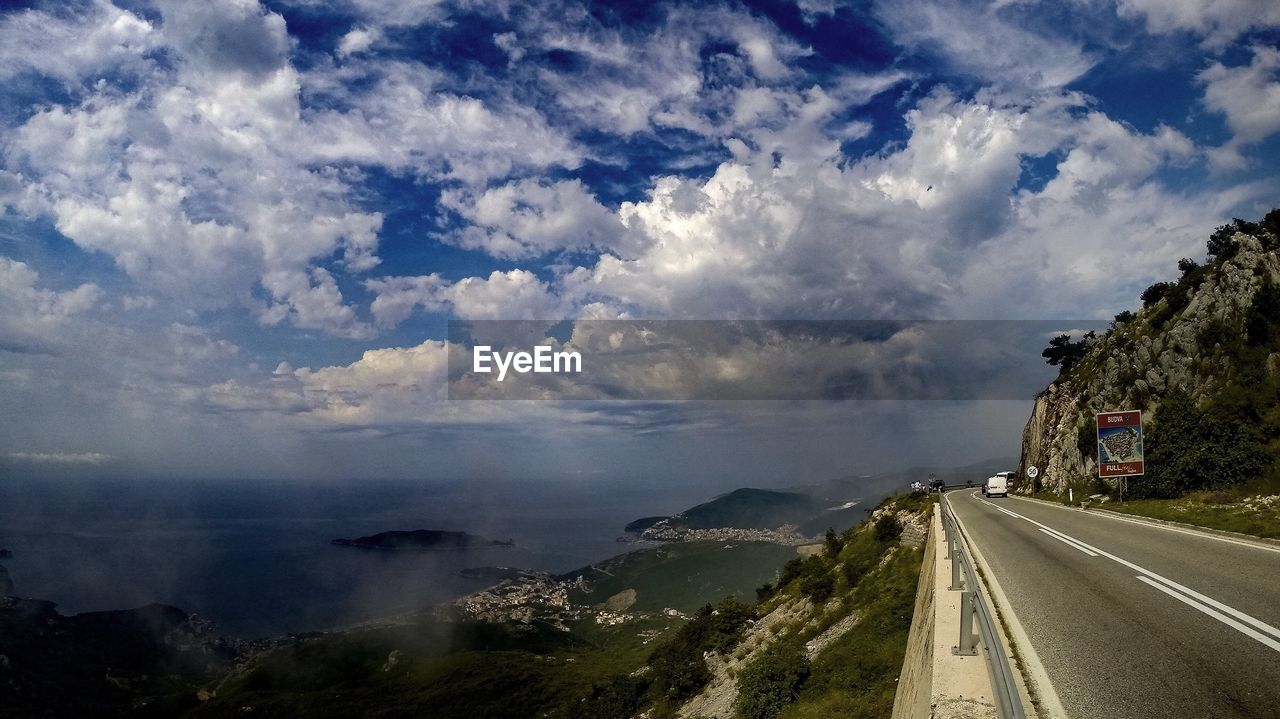 PANORAMIC VIEW OF ROAD AND SEA AGAINST CLOUDY SKY