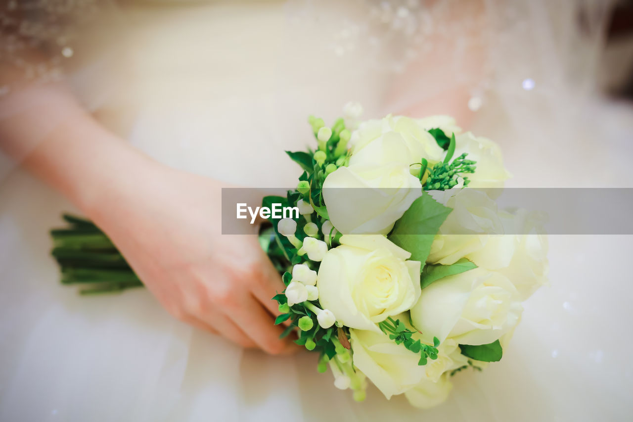 Midsection of bride holding bouquet