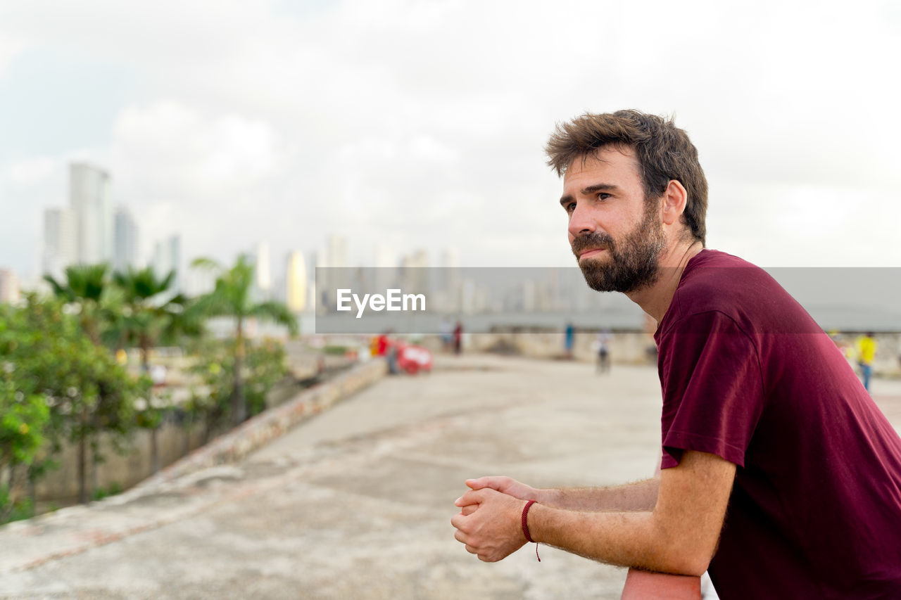 side view of young man standing against sky