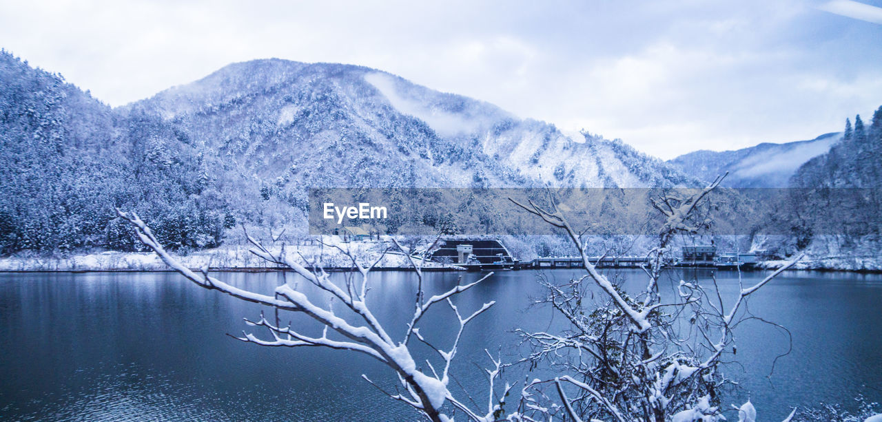Scenic view of frozen lake by mountains against sky