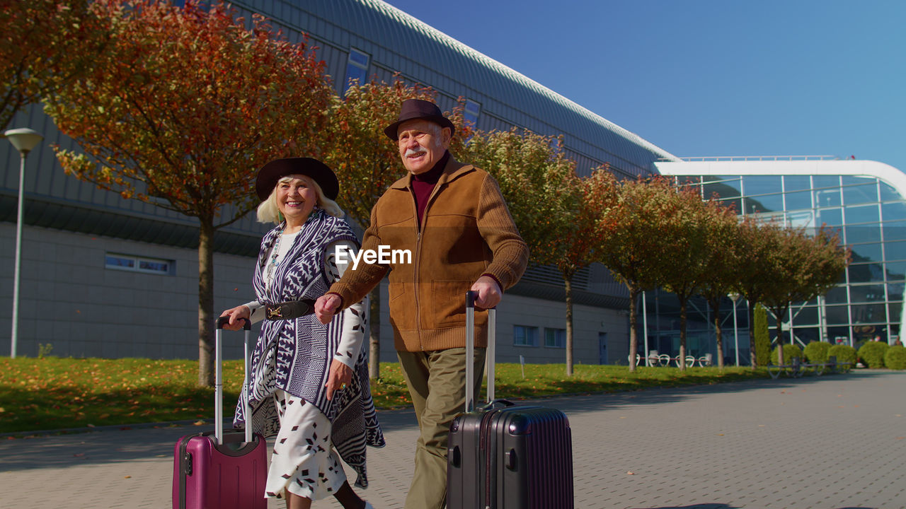 Low angle view of smiling couple walking out from airport