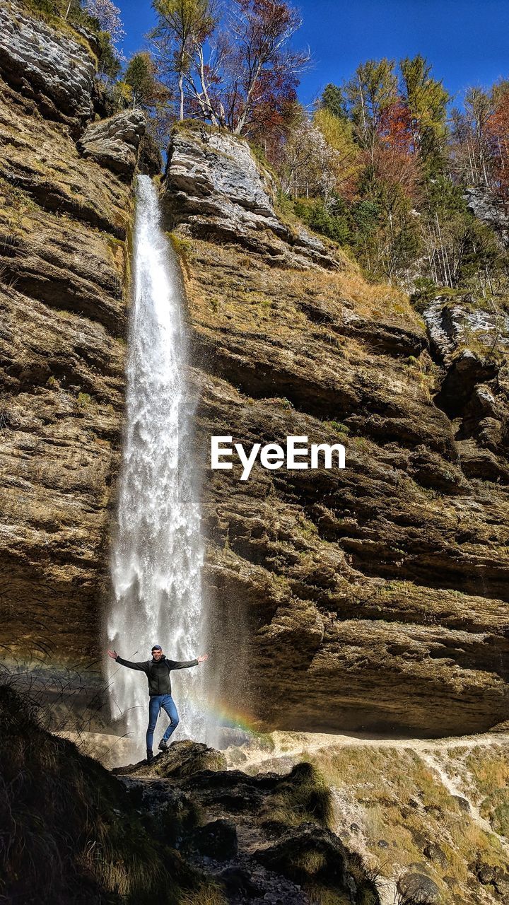 Low angle view of man standing against waterfall