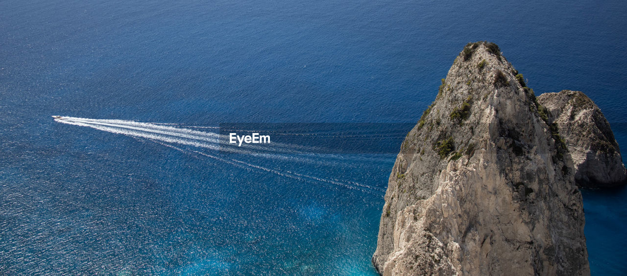 High angle view of speedboat passing rock formation