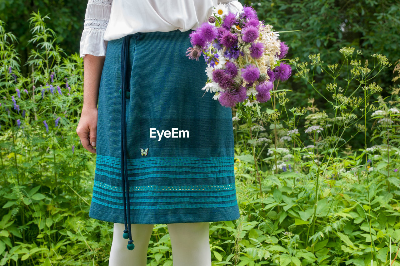 Midsection of woman standing by plants