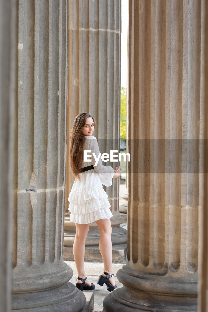 Portrait of young woman standing against columns