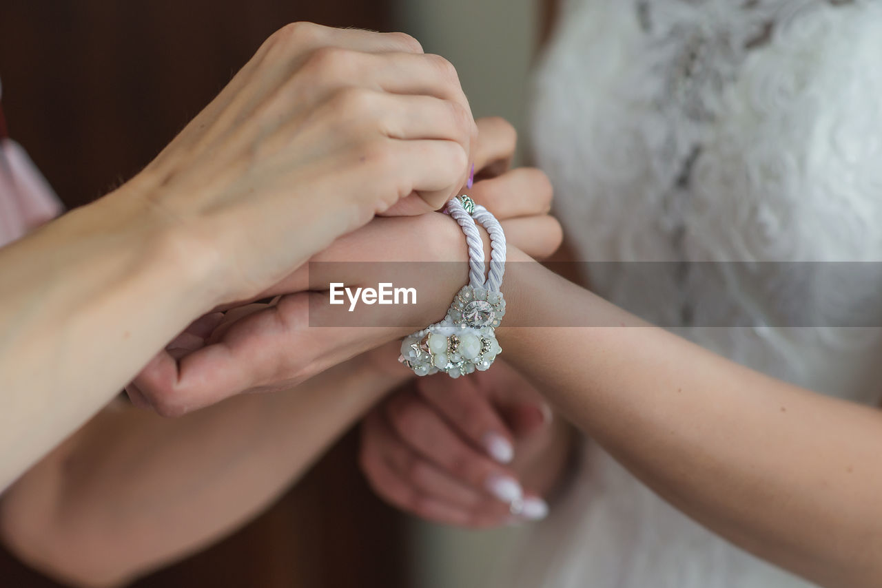 Close-up of woman getting bride dressed