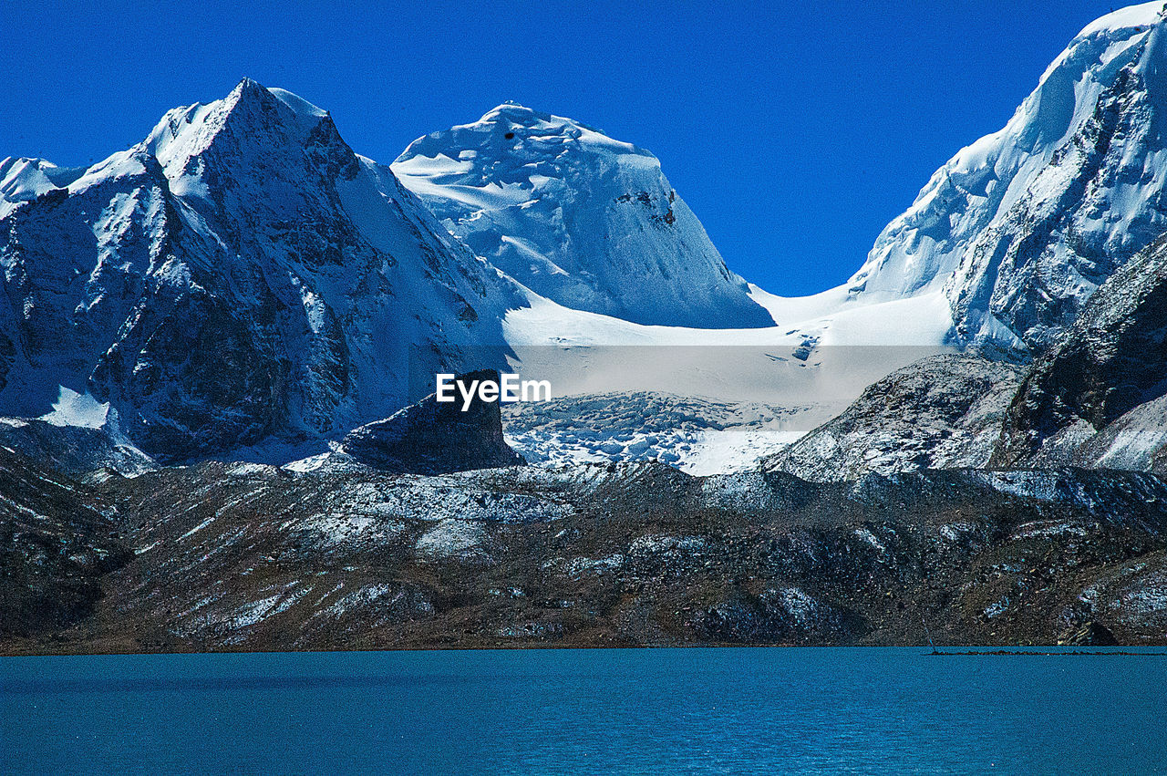 SNOW COVERED MOUNTAINS AGAINST BLUE SKY