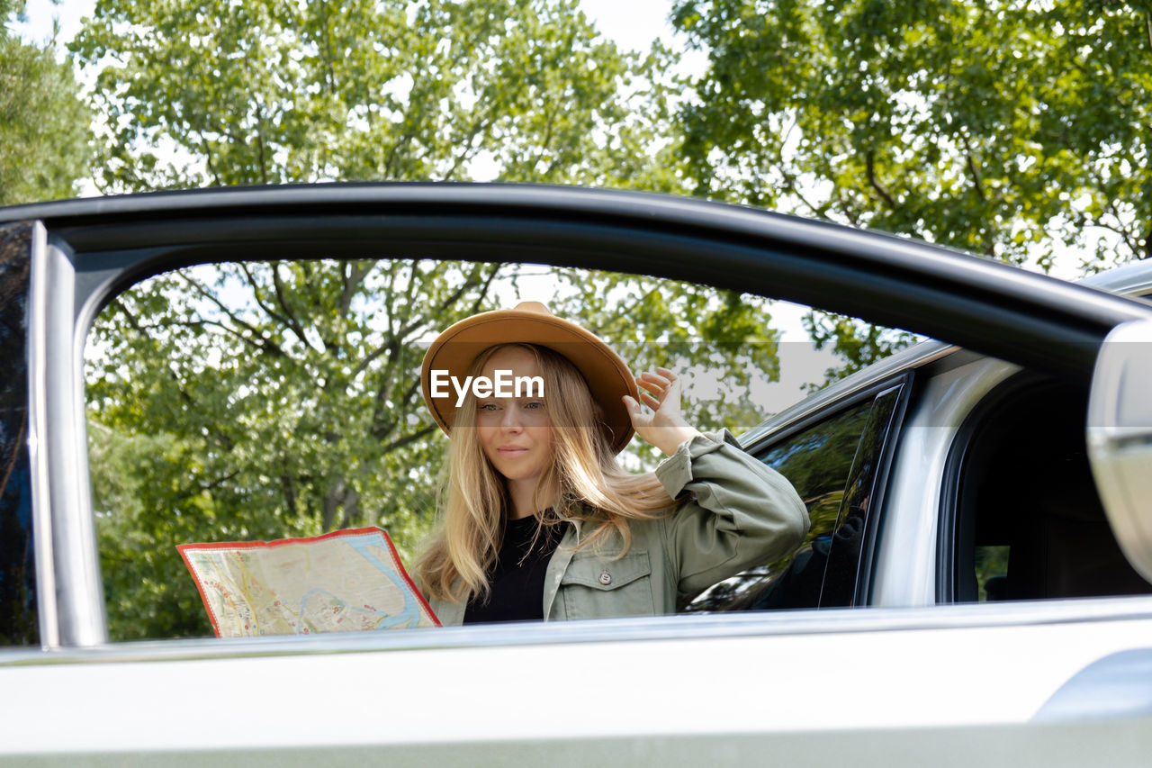 side view of young woman reflecting on car