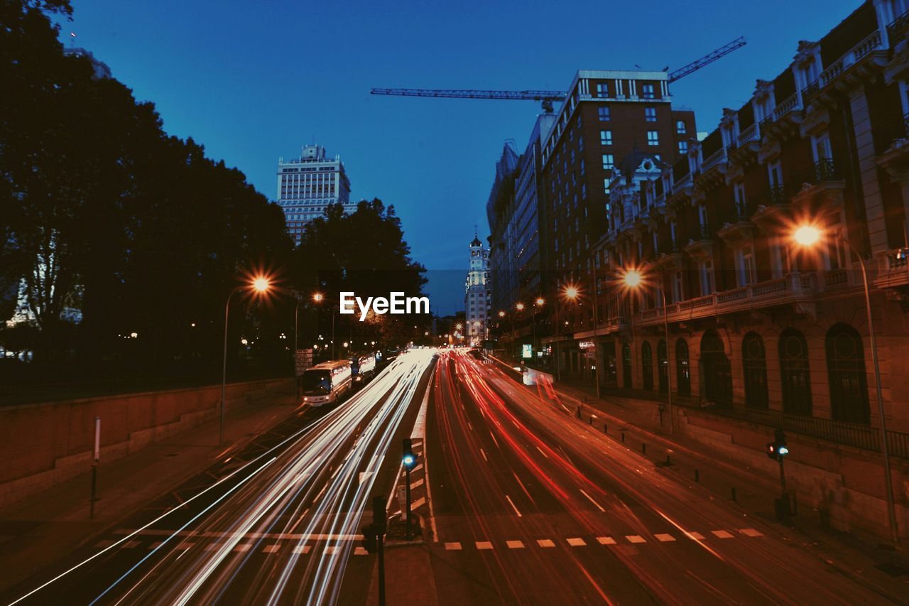 Light trails on road along buildings