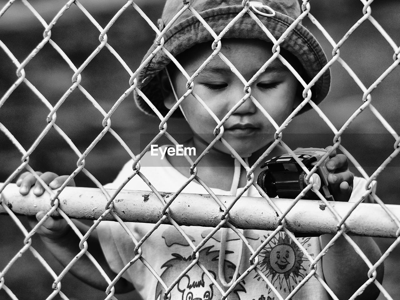 PORTRAIT OF A YOUNG MAN SEEN THROUGH CHAINLINK FENCE