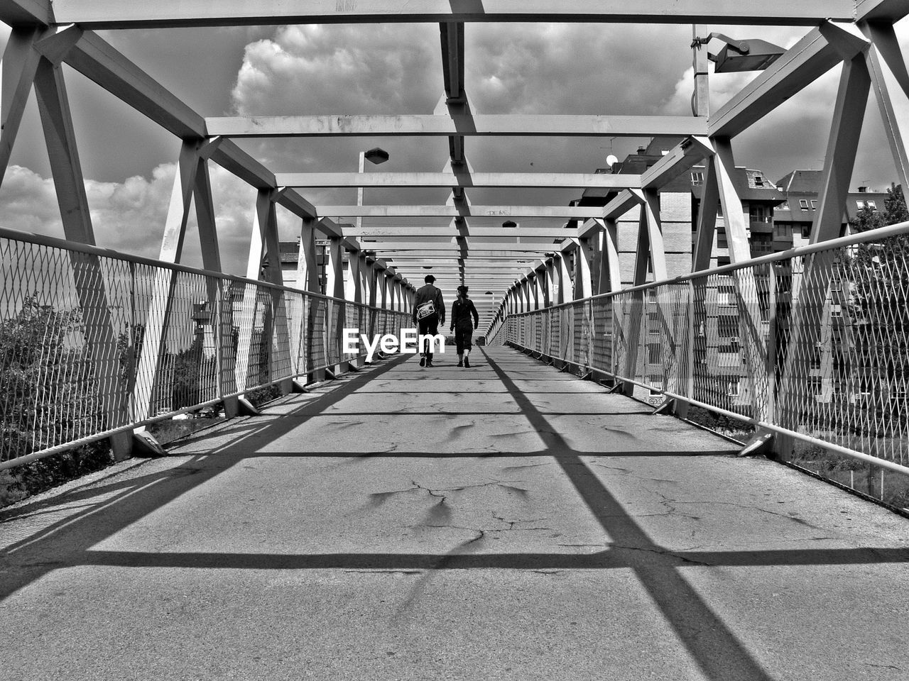 Rear view of man and woman walking on bridge