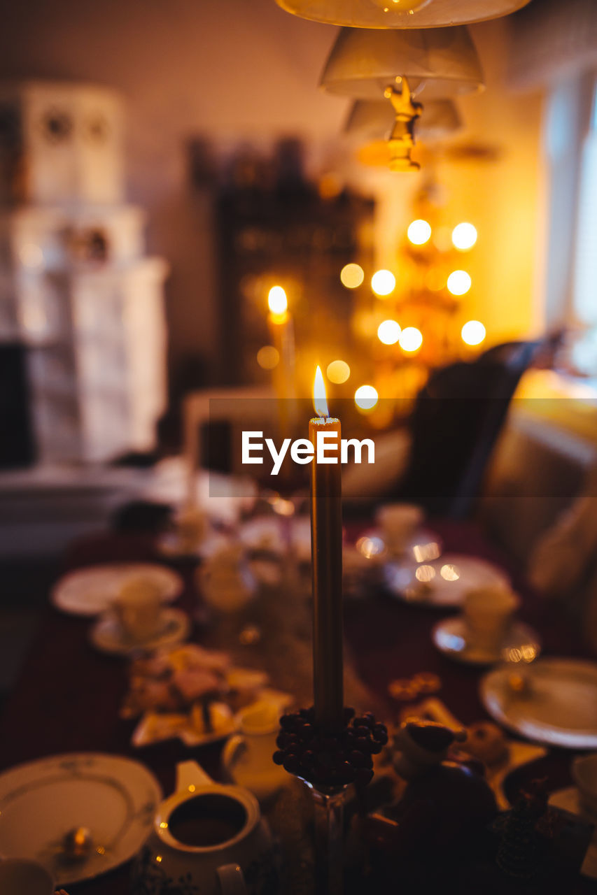 CLOSE-UP OF LIT CANDLES ON TABLE AT NIGHT