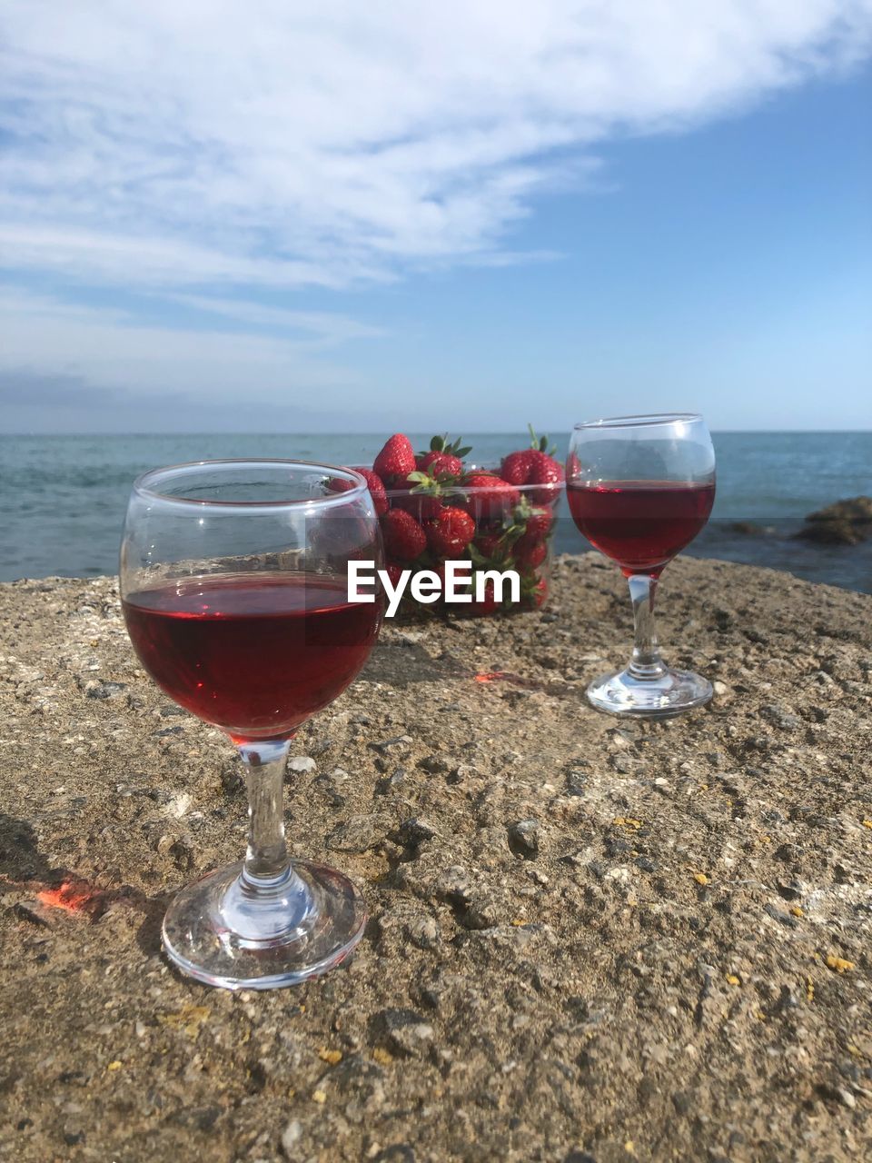 Wineglass on beach by sea against sky