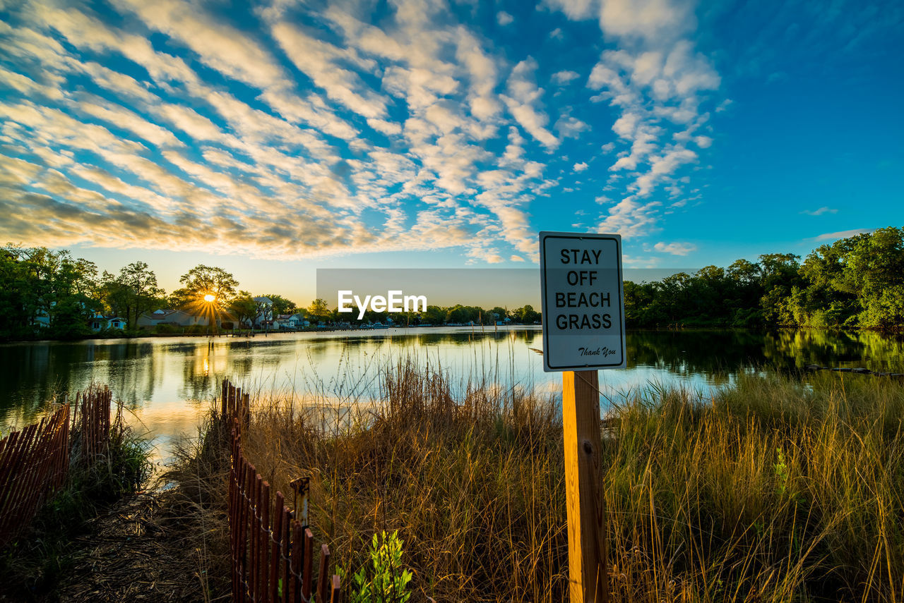 INFORMATION SIGN ON LAKE AGAINST SKY