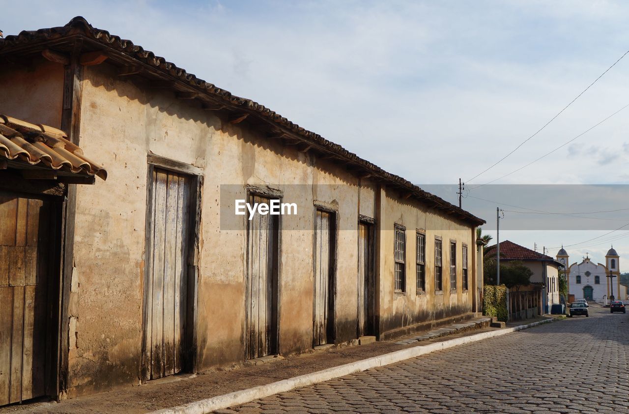 Exterior of old building by road against sky