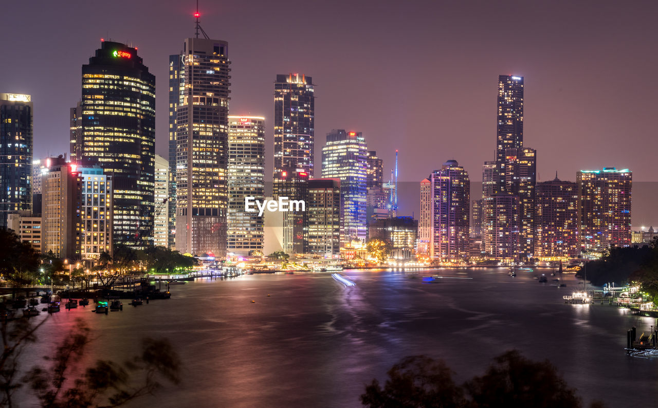 Illuminated buildings in city against sky at night