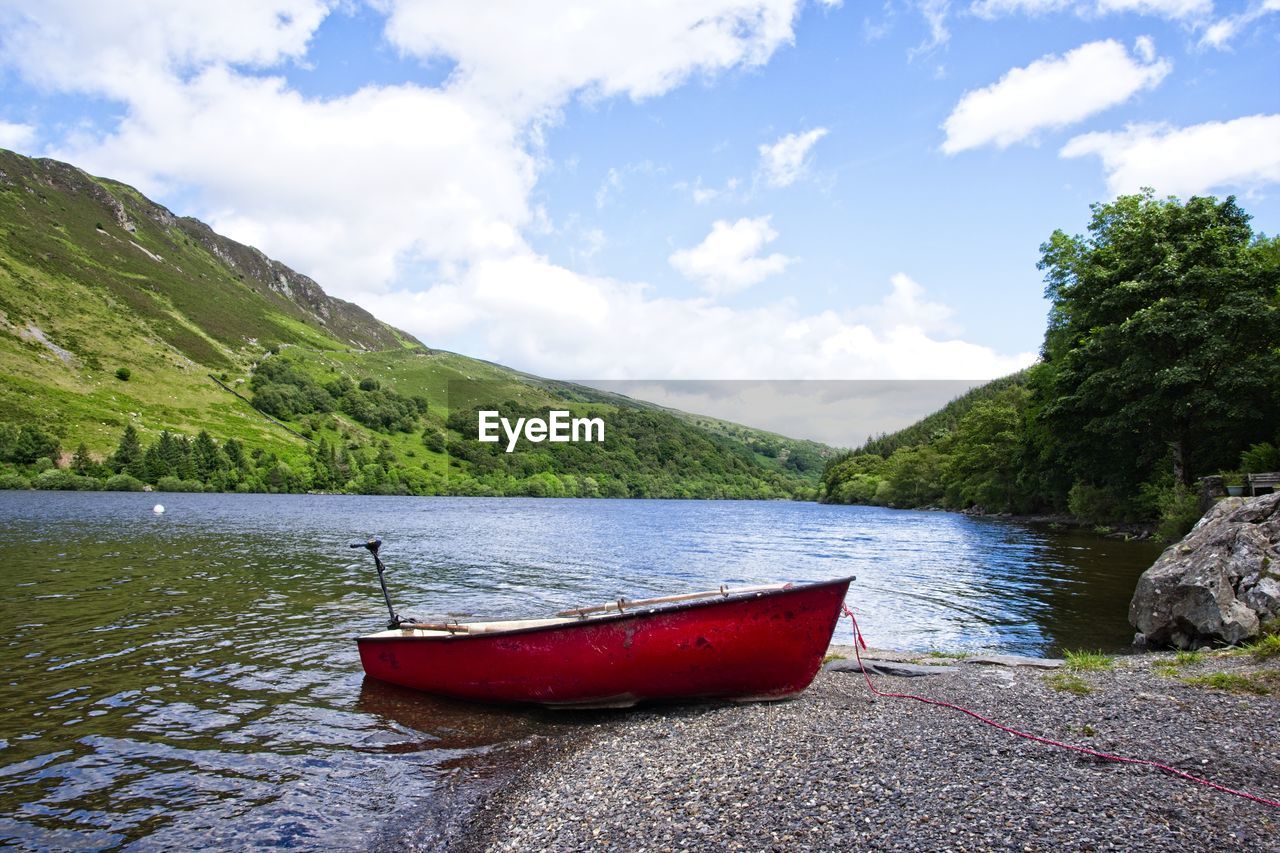 Boat moored on lake against sky