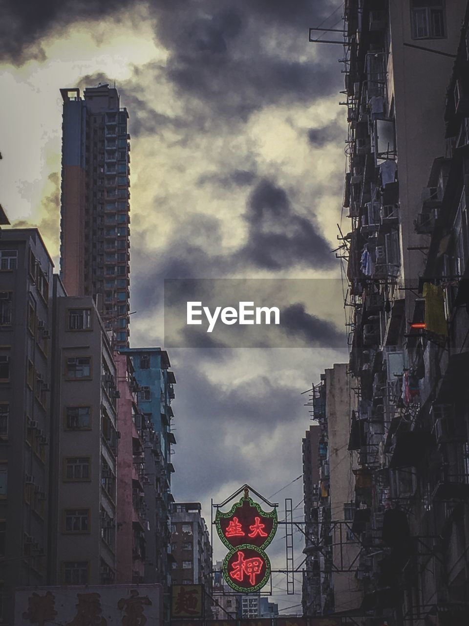 LOW ANGLE VIEW OF BUILDINGS IN CITY AGAINST CLOUDY SKY