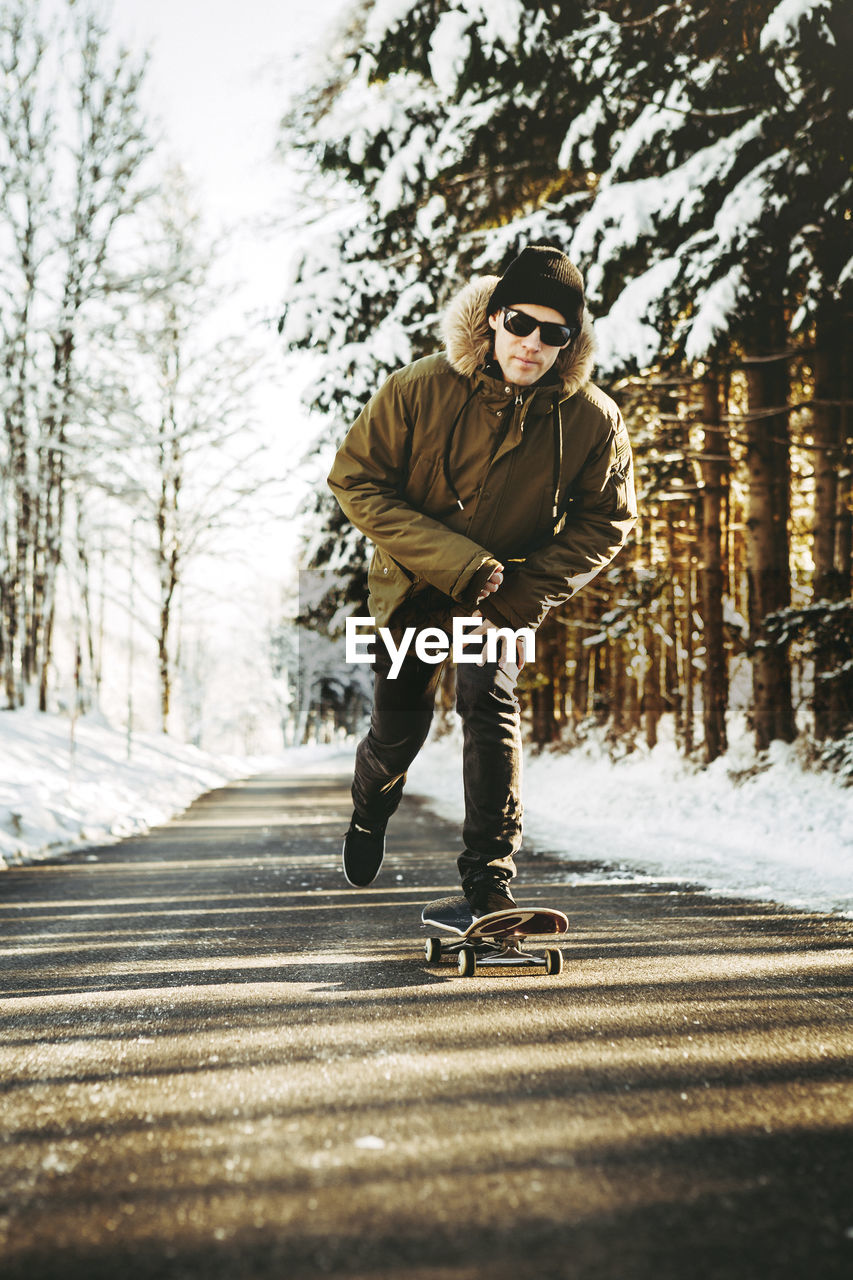 Full length of man skateboarding on road by snow