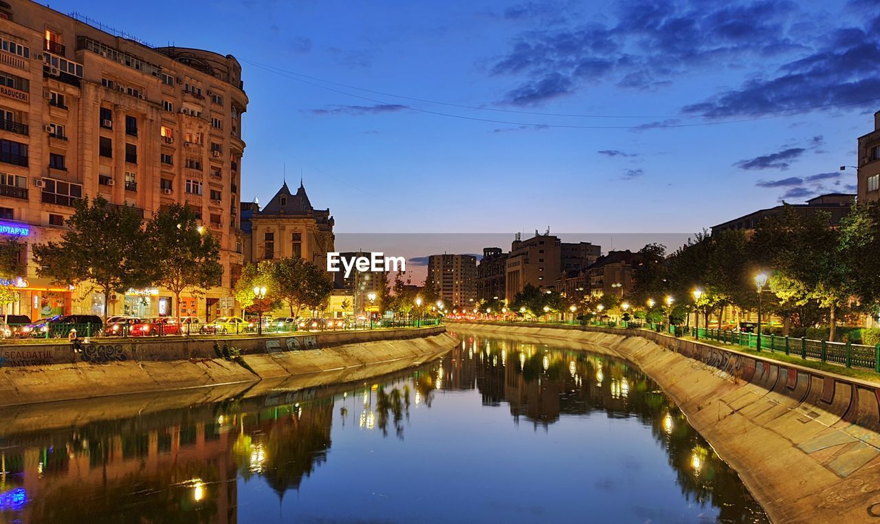 CANAL BY ILLUMINATED BUILDINGS AGAINST SKY AT NIGHT