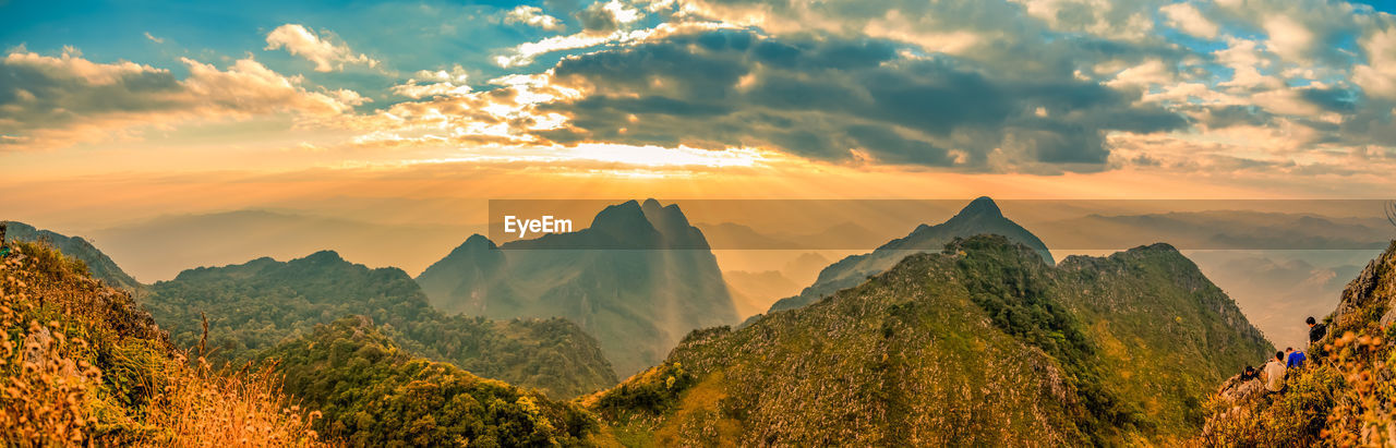 Panoramic beautiful scenic mountain range with blue sky, cloud and blast horizon sun with tourists