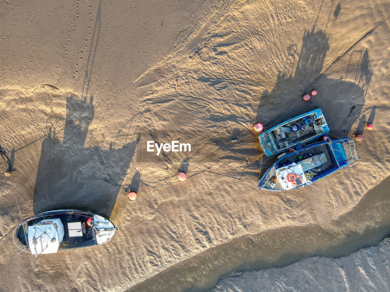 Overhead drone image of boats moored in muddy harbour