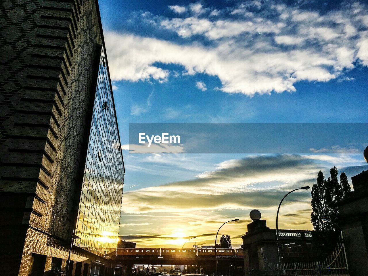 Low angle view of modern building against cloudy sky during sunset in city