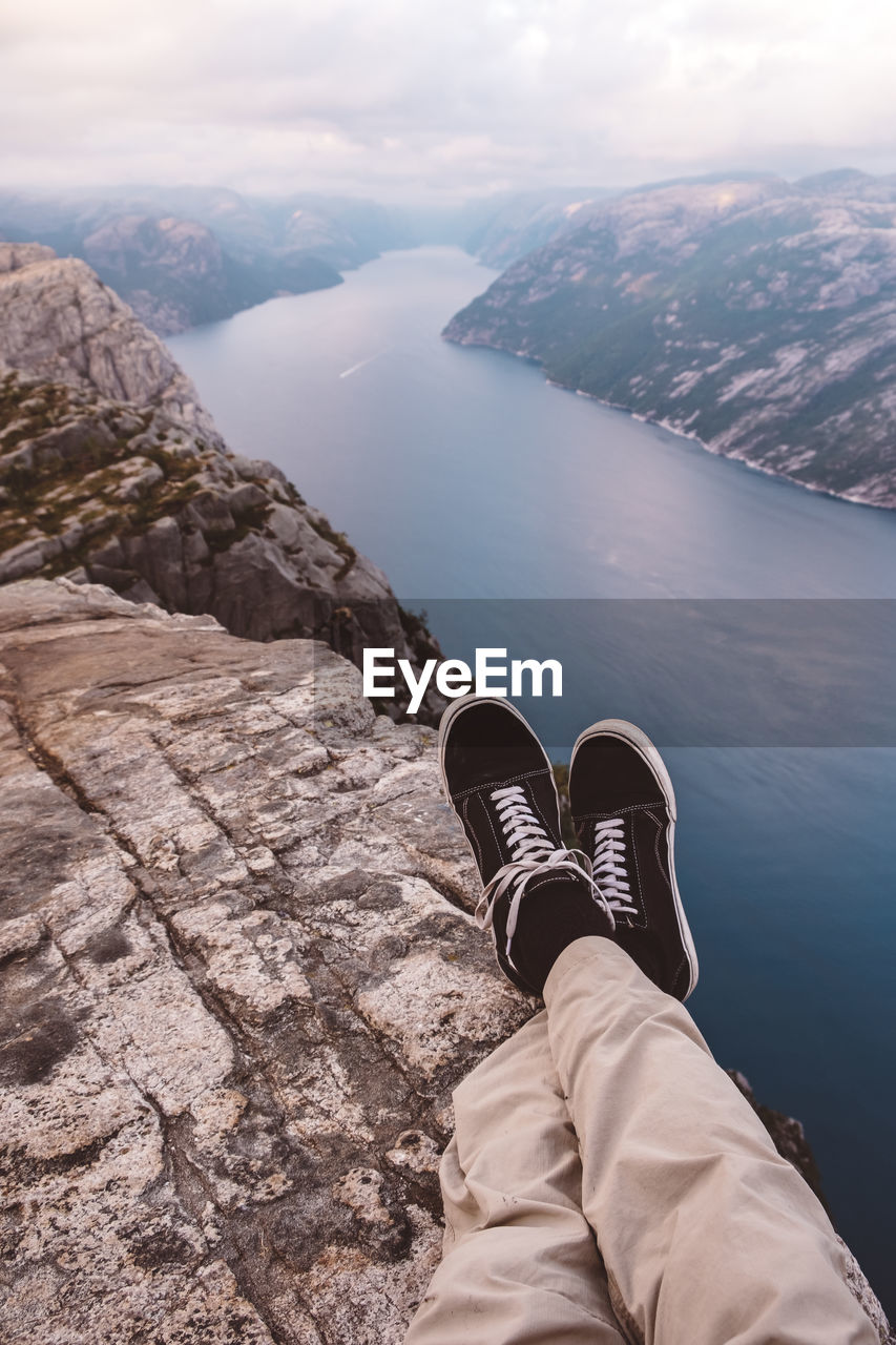 Person cross legged at edge of cliff with a fjords view in norway